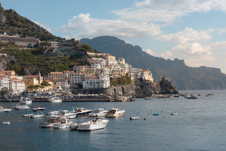 Boats float near the picturesque town on the Amalfi Coast under a bright sky.