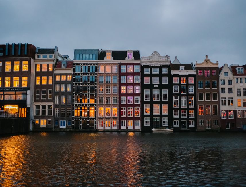 A picturesque view of Amsterdam's iconic canal houses reflecting off the water at dusk.