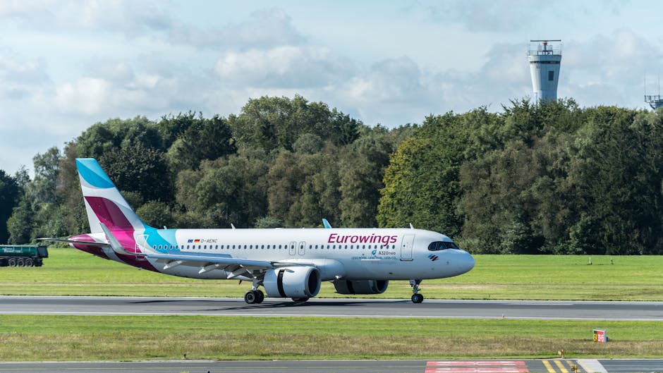 Eurowings Airbus A320neo on the runway at Hamburg Airport, Germany, with control tower in the background.