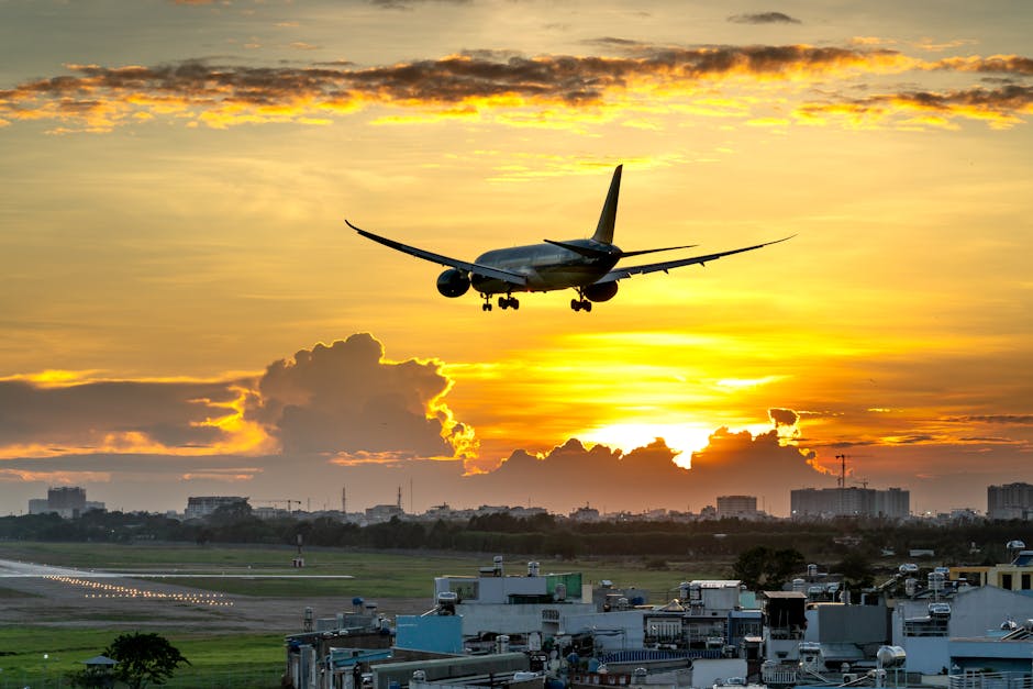 A dramatic image of an airplane landing against a vibrant sunset over a city skyline.