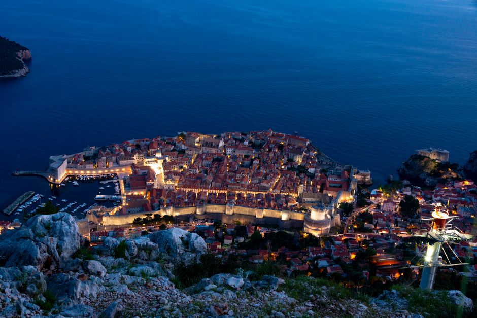 Stunning aerial view of Dubrovnik, Croatia, illuminated at twilight with the Adriatic Sea in the background.