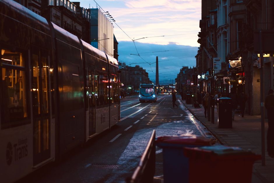 A dimly lit city street showcasing trams, rails, and urban architecture during the evening.