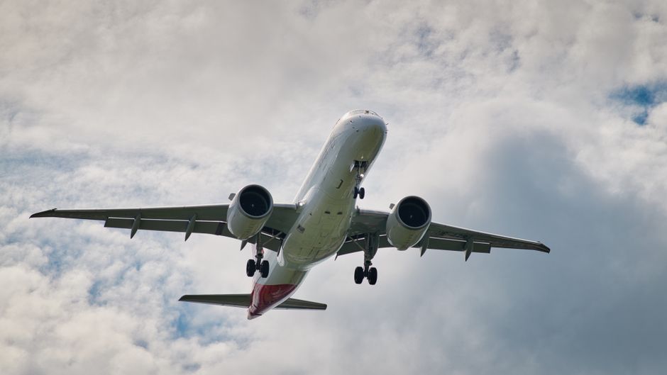 A commercial jet airliner ascending through a cloudy sky, capturing aviation dynamics.