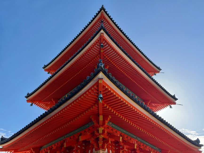 Captivating shot of a traditional red pagoda in Kyoto, Japan against a clear blue sky.