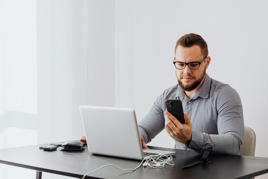 Professional man working at desk with laptop and smartphone, indoors.