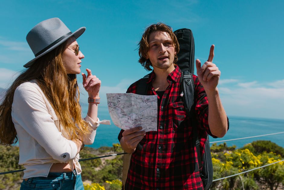 A couple exploring nature with a map, surrounded by scenic views and vibrant foliage.
