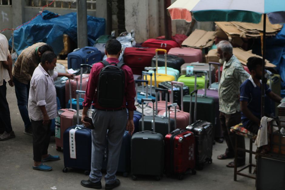 Street market scene with people browsing various colorful suitcases.