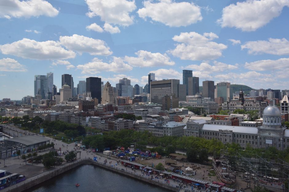 Aerial view of Montreal's skyline under a bright blue sky with fluffy clouds.