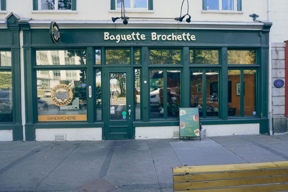 Charming street view of a French bakery called Baguette Brochette with green storefront and signage.