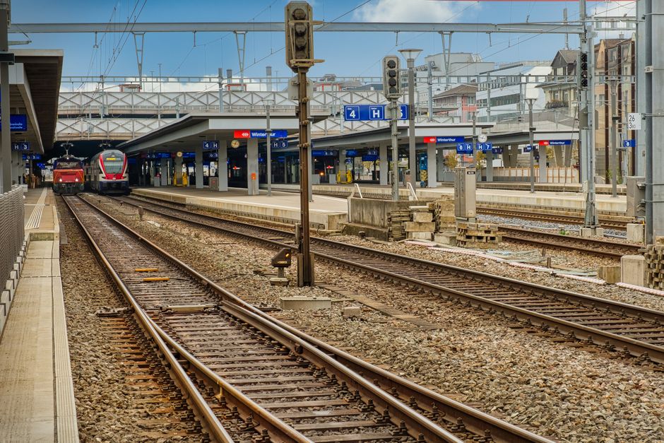 A vibrant urban train station with multiple platforms and trains arriving.