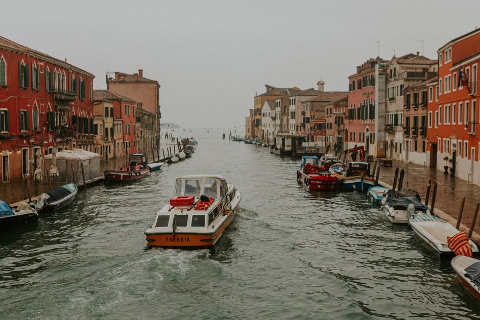 A canal scene in Venice with boats and colorful buildings on an overcast day.